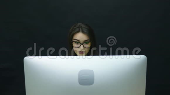 戴眼镜的女人在办公室里用电脑看着显示器开始高兴起来视频的预览图