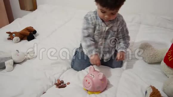 可爱的两岁小男孩玩储蓄罐把硬币放进去视频的预览图