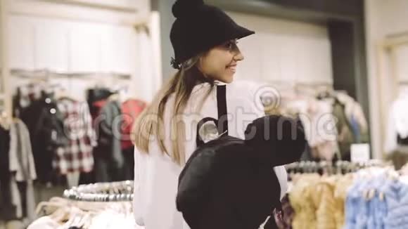 一个年轻女孩在镜子前的商店里试戴一顶帽子视频的预览图