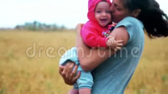 快乐的妈妈抱着微笑的孩子在田里拿着麦子视频的预览图