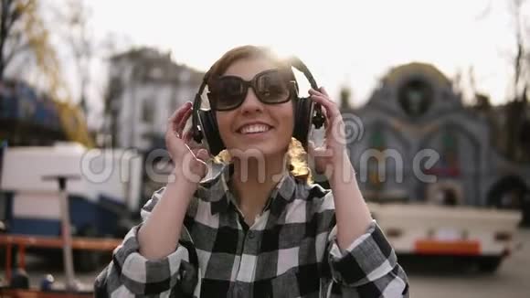 乐观快乐的女孩走在街上听着耳机里的好音乐她笑着跳舞视频的预览图