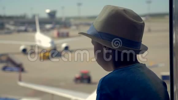 一个男孩看着机场的飞机跑道等待旅行关闭视频的预览图