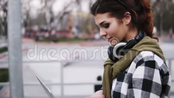开朗的年轻女孩手里拿着一台笔记本电脑穿过公园同时打字嘲笑和拥有视频的预览图