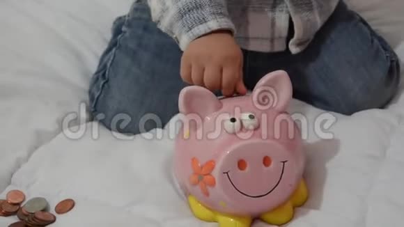 可爱的两岁小男孩玩储蓄罐把硬币放进去视频的预览图