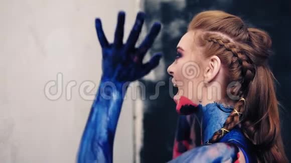那个穿胸罩的女孩用手擦去墙上的油漆感情上的喊叫侧视图视频的预览图
