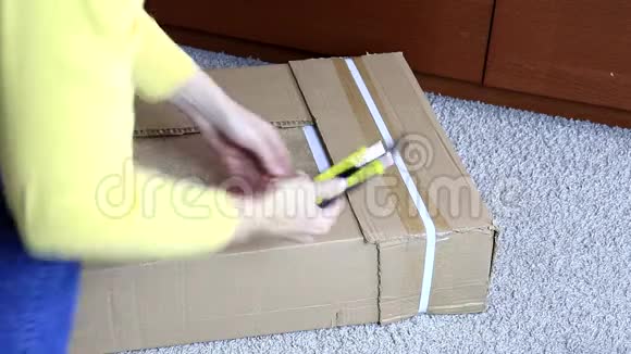 女人用建筑或办公刀打开一个装有新家具的纸板箱搬到新房子去买东西视频的预览图