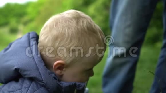 快乐可爱的小男孩在公园里看爸爸和相机视频的预览图