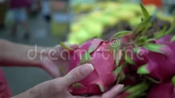 女人选择一个成熟的火龙果把它放在购物篮里女人在市场上的水果顾客关门视频的预览图