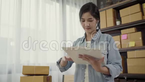 美丽聪明的亚洲青年企业家女企业家中小企业检查产品库存和写在剪贴板上工作视频的预览图