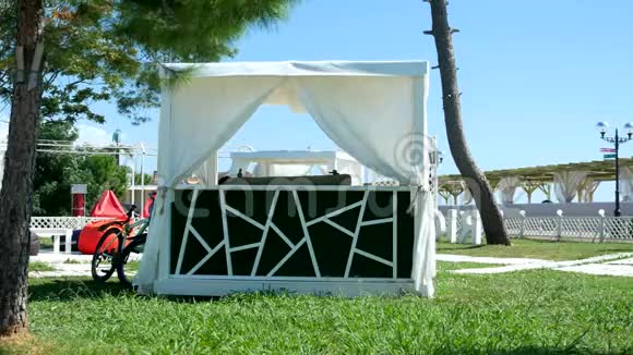 露台上有木制框架和白色窗帘以及海边沙滩上的躺椅在夏天阳光明媚的日子视频的预览图