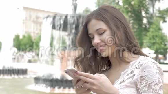 迷人的年轻女子使用她的触摸屏手机对自己微笑视频的预览图