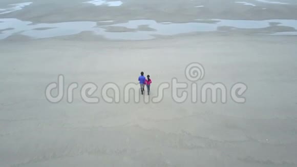 父亲和女儿手牵着手在海滩上散步视频的预览图