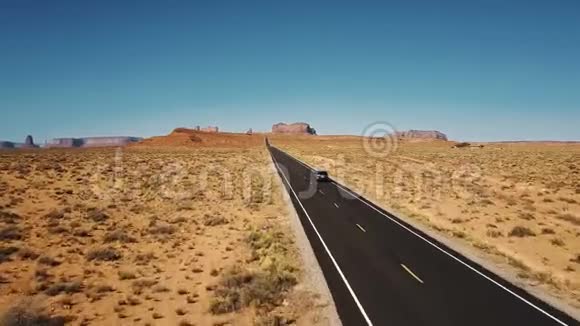 无人机跟随银色的汽车沿着令人惊叹的美国沙漠景观空公路道路在纪念碑谷美国视频的预览图