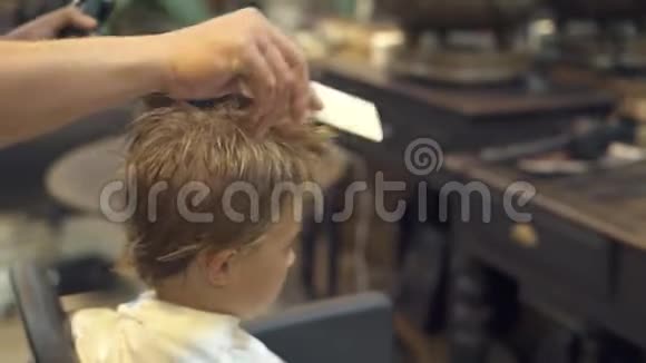 理发师在理发店给小男孩理发前梳头儿童用梳子理发视频的预览图