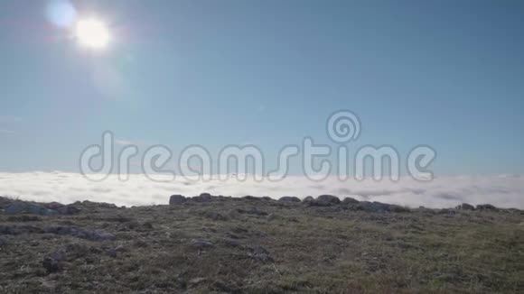 年轻的白种人戴着太阳镜的女人在阳光明媚的日子在云层上方的山上慢跑天空奔跑视频的预览图