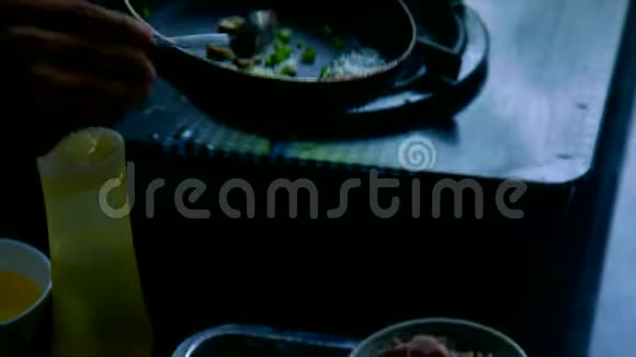 人们把碗里的食材放在黑锅上做菜视频的预览图