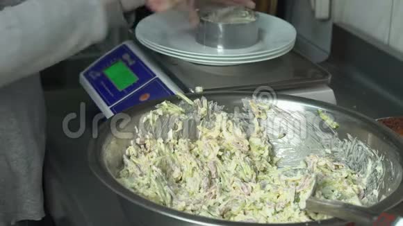 厨师把一份肉沙拉和蔬菜放在盘子里放在餐馆厨房的秤上视频的预览图