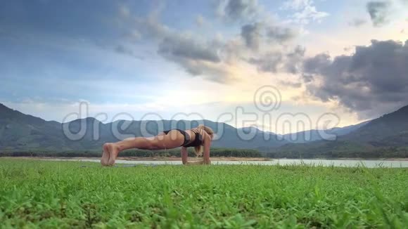 侧视女孩躺在瑜伽姿势的弯曲手臂和脚在草地上视频的预览图