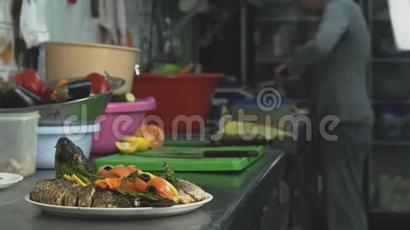 餐厅或咖啡厅的厨房里有烤鱼和蔬菜厨师在后台工作视频的预览图