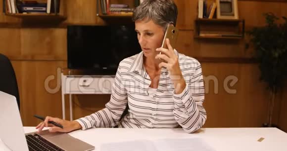 商务女性在使用笔记本电脑4k时使用手机视频的预览图