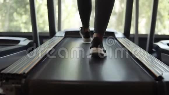 在黑色球鞋上靠近女性的脚健身女孩在跑步机上行走肌肉发达的女人视频的预览图