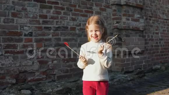 小女孩把纸唇放在砖墙旁边的棍子上视频的预览图