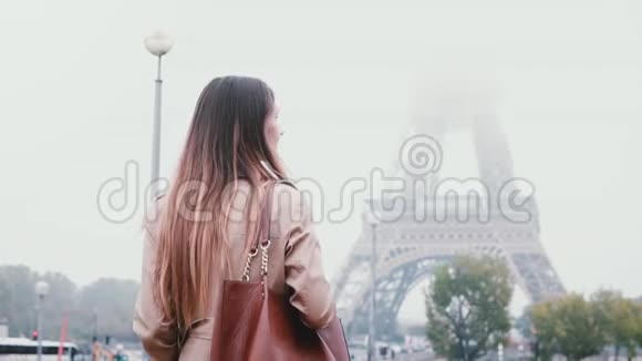 清晨雾蒙蒙的法国巴黎市区散步的年轻时尚女性的后景看埃菲尔铁塔视频的预览图