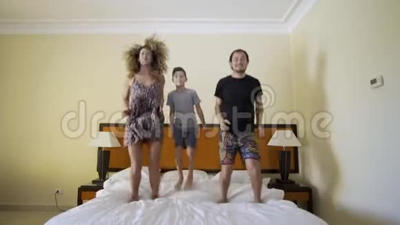 幸福的一家人在床上跳幸福的家庭观念爸爸妈妈和小男孩跳在床上视频的预览图