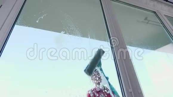 透过窗户微笑的白种人美丽的女人戴着手套用特殊的拖把清洗窗户用一个特殊的拖把视频的预览图