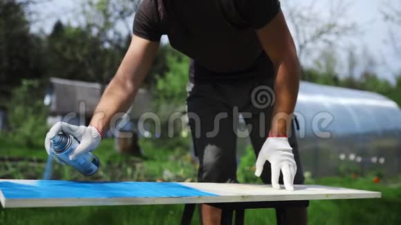 人手里的工作手套用喷罐把油漆喷到室外的木制表面上人在视频的预览图