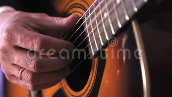男人弹声吉他弹吉他琴弦的手的特写视频的预览图