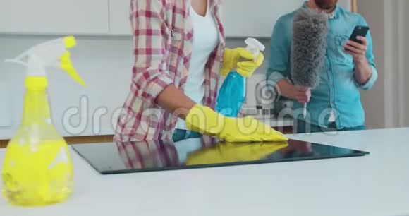 用除脂剂喷雾剂和一名戴黄色橡胶手套的妇女的喷雾器清洁厨房的烹饪面板视频的预览图