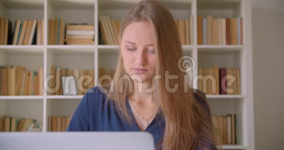 年轻漂亮的白种人女商人用笔记本电脑在办公室里看着相机开心地笑着特写照片视频的预览图