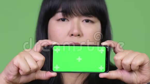 快乐超重的亚洲女人在看电话视频的预览图