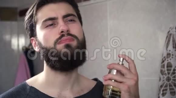 人泼香水特写英俊严肃的男人在脖子上喷香水在镜子前的浴室里视频的预览图