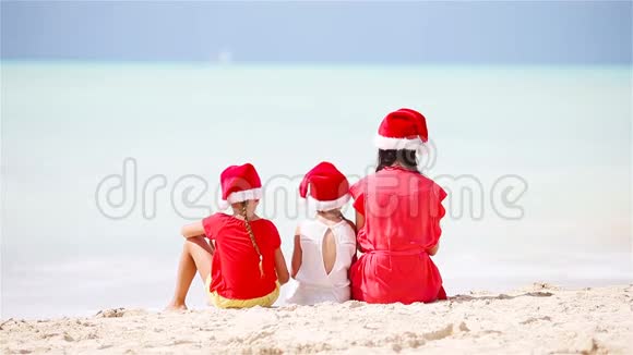 快乐美丽的家庭戴着红色圣诞帽在热带海滩庆祝圣诞节妈妈和孩子们享受圣诞假期视频的预览图