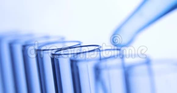化学实验室测试移液管将透明化学物质滴入蓝色试管中视频的预览图