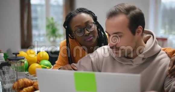 年轻的跨国夫妇在咖啡馆里一起用笔记本电脑工作视频的预览图