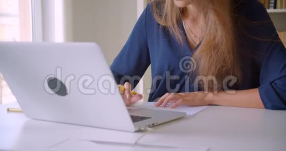 年轻有魅力的高加索女商人用笔记本电脑在室内做笔记的特写照片视频的预览图