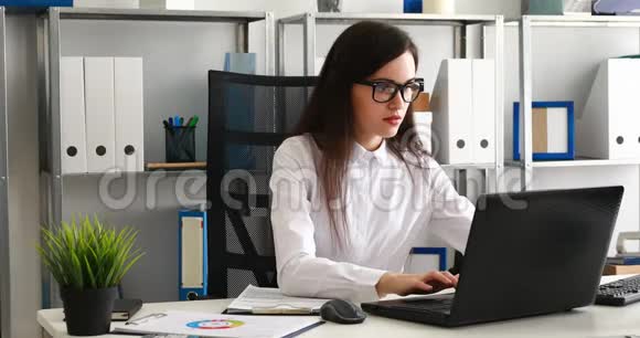 女商人摘下眼镜看着相机在现代办公室里用笔记本电脑工作视频的预览图