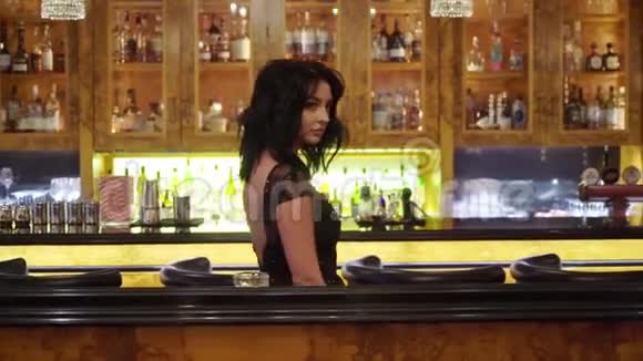 在餐馆或酒吧穿黑色晚礼服的年轻黑发女子视频的预览图