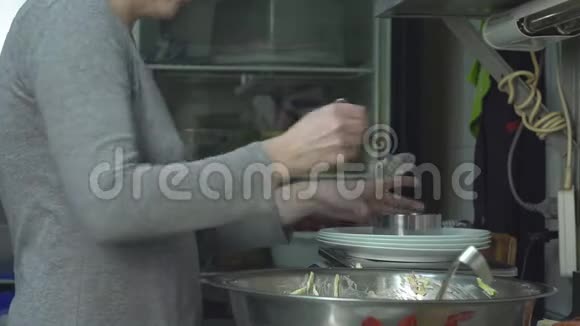 厨房里的一个厨师把沙拉的分量按克计放到桌子上视频的预览图
