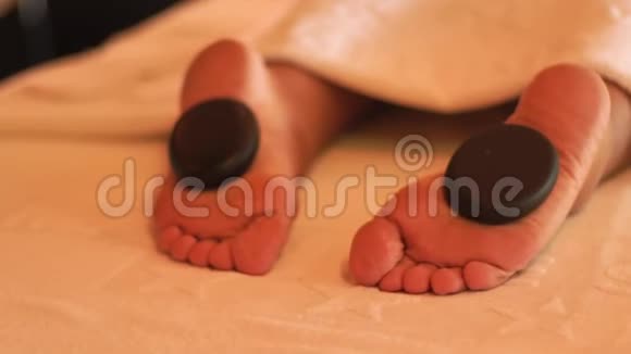 豪华水疗沙龙的石材按摩和治疗在温泉沙龙接受石头按摩的年轻女性的贴身脚身体视频的预览图