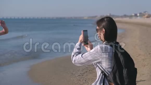 妈妈在她儿子在海边散步的手机上拍了一张照片和视频视频的预览图