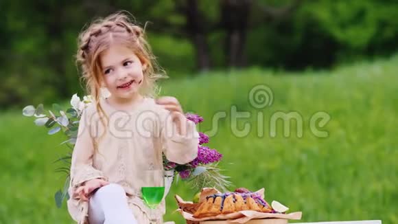 快乐的女孩穿着漂亮的浅色连衣裙发型凌乱坐在装饰好的桌子上吃着一个巧克力蛋糕视频的预览图