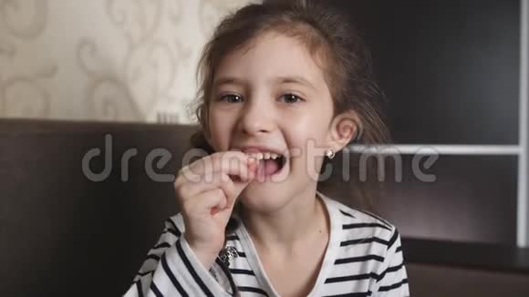 一个可爱的小女孩摇摇晃晃地摇晃着她松动的牙齿想把它拔掉视频的预览图