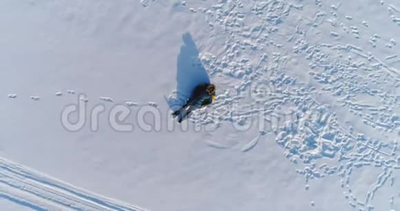 女人在雪地里躺在管子上摄像机慢慢升起空中录像视频的预览图