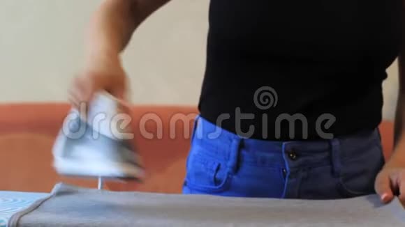 女孩在熨衣板上用熨斗烫衣服视频的预览图