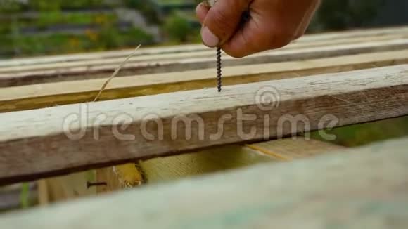 安装旋入式木板的人库存录像男人用螺丝刀把一个螺丝钉拧进板里视频的预览图