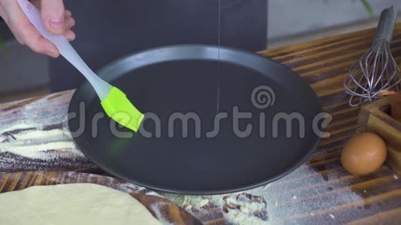 厨师在烤盘上倒入橄榄油用刷子铺在厨房桌子上烤饼用橄榄油蛋糕视频的预览图